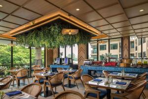 a restaurant with tables and chairs and a bar at The Proud Karon Beach Phuket Trademark Collection By Wyndham in Karon Beach