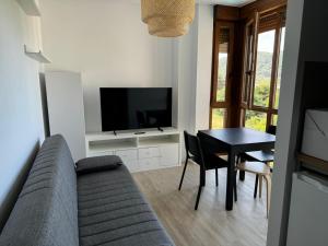 a living room with a couch and a table with a television at Apartamentos Boutique Don Miguel in Noja