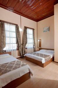 a bedroom with two beds and two windows at Konak Hotel Kaleiçi in Antalya