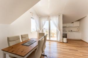 a kitchen and dining room with a wooden table and chairs at Apartments Barbati in Novalja