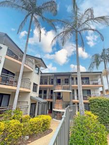 a building with palm trees in front of it at Beaches Holiday Resort in Port Macquarie +20 photos