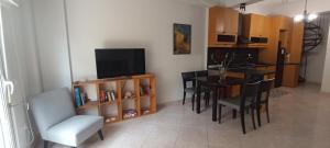 a kitchen and dining room with a table and a television at Bougainvillea Apartment Spacious Family Home in Zakynthos Town in Zakynthos