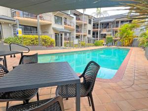 a table and chairs next to a swimming pool at Beaches Holiday Resort in Port Macquarie