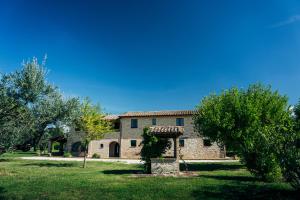un gran edificio de piedra en un patio con árboles en Valle di Assisi Villa Privata, en Tordandrea