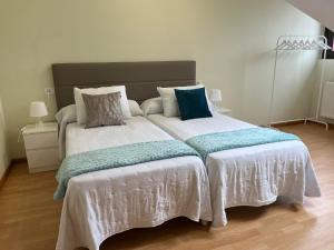 a bedroom with a large bed with white sheets and blue pillows at La Posada de LLanes in Posada de Llanes