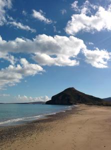 a sandy beach with a hill in the distance at Surf Beach Apartments in Palekastron