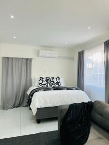 a white bedroom with a bed and a couch at Easy Living Apartment 2 in Rundu