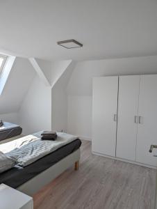 a white bedroom with a bed and white cabinets at Wohnung am Kasinopark in Georgsmarienhütte +6 photos