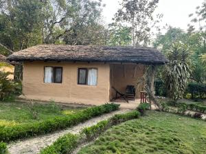 ein kleines Haus mit einem Strohdach im Hof in der Unterkunft Bardia dolphin home in Bhurkīā
