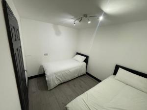 two beds in a small room with white walls at Four Bedrooms and Two Bathrooms up to Nine People in Birmingham