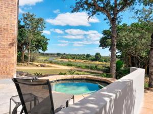 a swimming pool with a table and chairs next to a fence at Tswenyane Kruger Riverview Apartments in Marloth Park