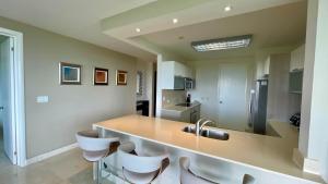 a kitchen with a counter with a sink and some chairs at Apartment with Spectacular Ocean Jungle Views in Playa Bonita Village