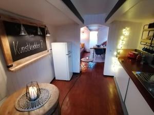 a kitchen with a table and a white refrigerator at Schute "Kunstkudder" im Hansehafen in Stade