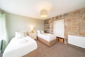 a bedroom with two beds and a brick wall at Eden View Estate - Clubhouse Cottage in St. Andrews