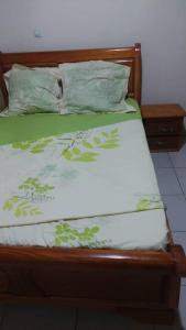 Cama con sábanas y almohadas verdes y blancas en LIKARLELoc, en Edéa