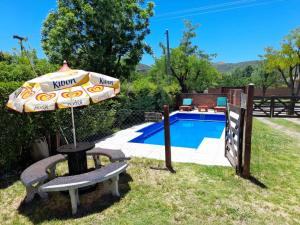 een parasol en een bank naast een zwembad bij Cabaña La Cumbre Palermo in La Cumbre