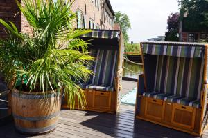 two chairs and a potted plant on a deck at Schute "Kunstkudder" im Hansehafen in Stade