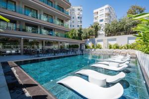 a hotel pool with white chairs and tables at Awen Lara Hotel in Antalya