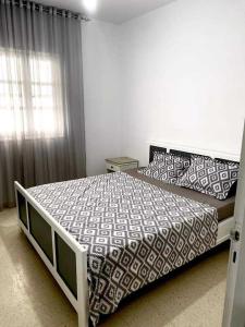 une chambre avec un lit avec une couette noire et blanche dans l'établissement ResidenceHbiba, à Ḩammām al Ghazzāz