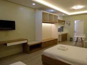a bedroom with a bed and a tv and a kitchen at Karas Pension House East in Tuguegarao City