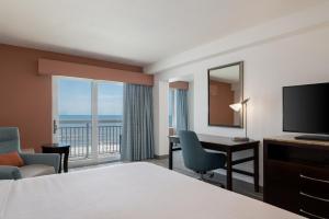 a hotel room with a bed and a desk and a television at Hilton Garden Inn Daytona Beach Oceanfront in Daytona Beach