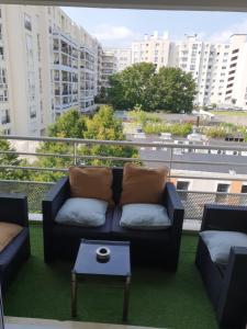 a couch and a table on a balcony with buildings at "Cosy & Modern" Logement avec parking privé et proche métro Paris ! in Le Kremlin-Bicêtre
