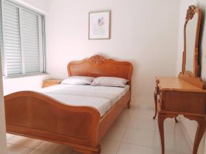 a bedroom with a wooden bed and a table at Ap com sacada à beira mar Praia mansa in Matinhos