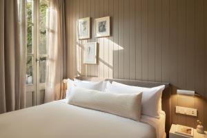 a bedroom with a bed with white pillows and a window at Hotel Casa Teva Barcelona in Barcelona
