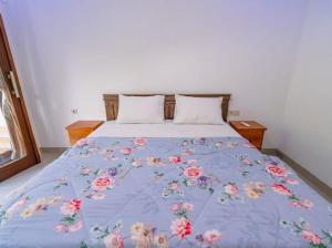 a bed with a blue blanket with flowers on it at umahananda in Mambat