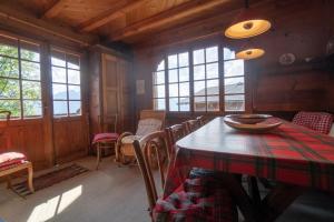 ein Esszimmer mit Tisch, Stühlen und Fenstern in der Unterkunft Tanière in Gryon