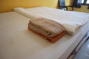 a brown towel sitting on top of a bed at Tange Guest House in Ruteng