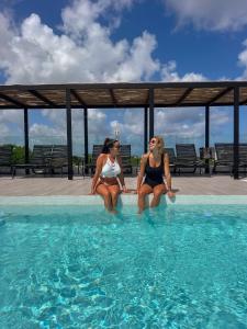 two women sitting on the edge of a swimming pool at Coralia Boutique Hotel Cozumel in Cozumel