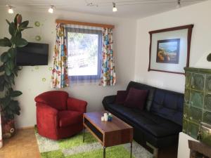 a living room with a black couch and a red chair at Das Sunnhäusl in Mariapfarr
