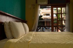 a bed with white pillows in a room with a window at Pousada Aquarela do Mar in Abraão