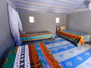 una camera con tre letti con coperte colorate di "Par 4 Chemins" - Atypical stopover a Nouakchott