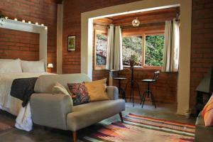 une chambre avec un lit, un canapé et une fenêtre dans l'établissement Chalé Ametista com ofurô e lareira, Santo Antônio do Pinhal, à Santo Antônio do Pinhal