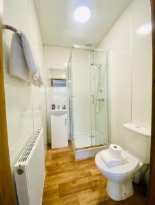 a white bathroom with a shower and a toilet at Tulip Cabin with Hot Tub in York