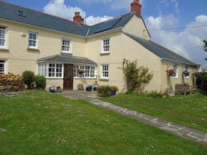 une grande maison blanche avec une pelouse devant dans l'établissement Brick Cottage, à Helston