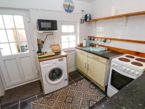 une cuisine avec une machine à laver et un lave-linge dans l'établissement Brick Cottage, à Helston