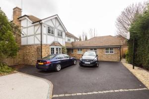 two cars parked in a parking lot in front of a house at Stunning Private en-suite studio in Cobham in Cobham
