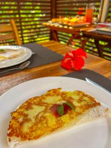 a slice of pizza on a white plate on a table at Vila Carmem in Fernando de Noronha
