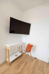 a chair and a desk with a television on a wall at Le Repaire in Montigny-le-Gannelon