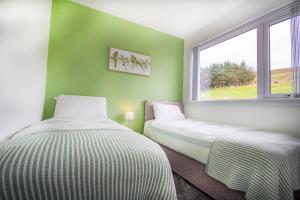 twee bedden in een kamer met groene muren en een raam bij Sunnyhill Cottage in North Erradale