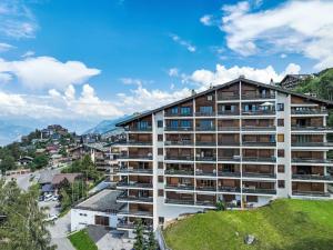 an apartment building in a city with mountains in the background at Apartment Chaedoz 65 by Interhome in Nendaz