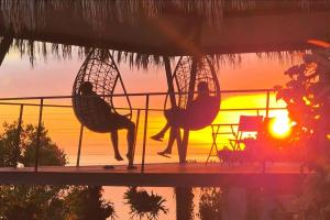 a person sitting in a hammock on a patio with the sunset at Torre Bella Gardens in Arco da Calheta