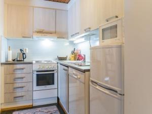 eine Küche mit weißen Schränken und einem Edelstahlkühlschrank in der Unterkunft Holiday Home Vuokatinportti a 11 by Interhome in Lahdenperä