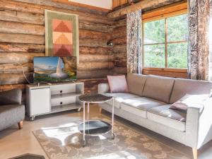 ein Wohnzimmer mit Sofa und Fernseher in der Unterkunft Holiday Home Vuokatinportti a 11 by Interhome in Lahdenperä
