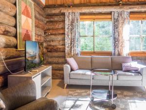 ein Wohnzimmer mit Sofa und Fernseher in der Unterkunft Holiday Home Vuokatinportti a 11 by Interhome in Lahdenperä