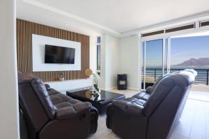 a living room with two leather chairs and a television at Portico 1006 Beachfront Apartment with Panoramic Views in Cape Town