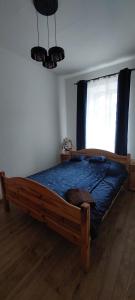 a bedroom with a wooden bed with a blue comforter at Apartament Ustroń Daszyńskiego in Ustroń